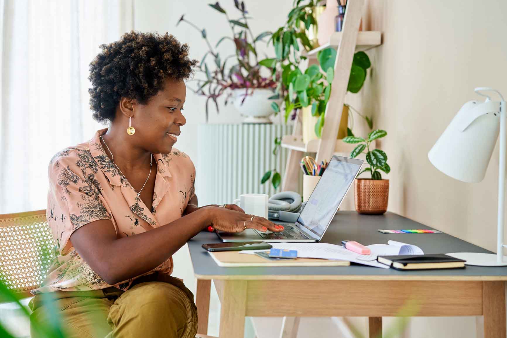 A woman sits at her home office desk working from home on a laptop