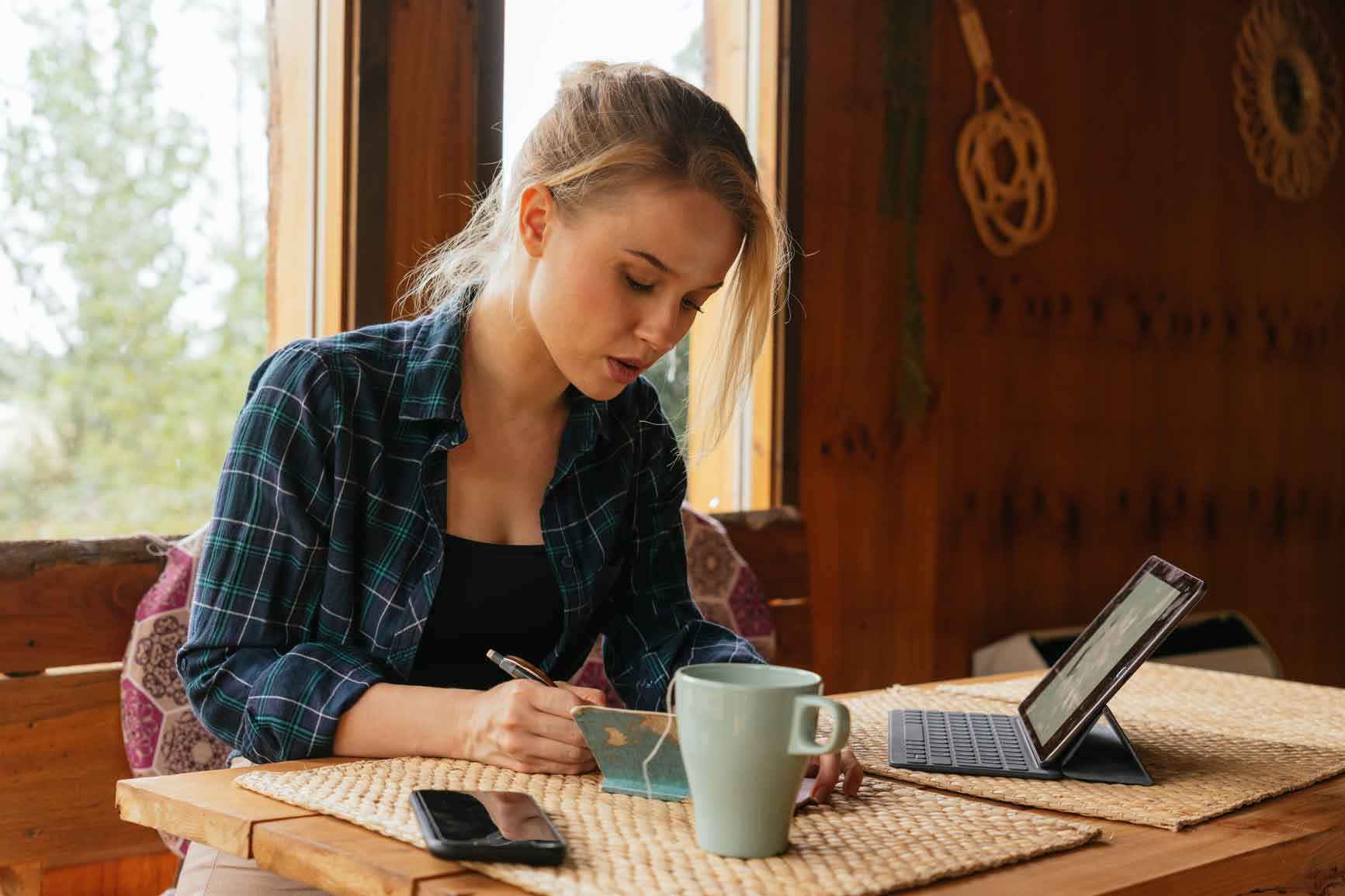 Young blonde woman taking notes in a notebook.